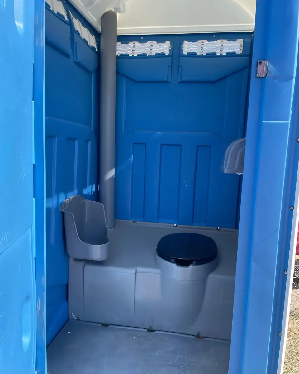 Inside a standard portable toilet: seat, urinal, tissue holder and vent stack