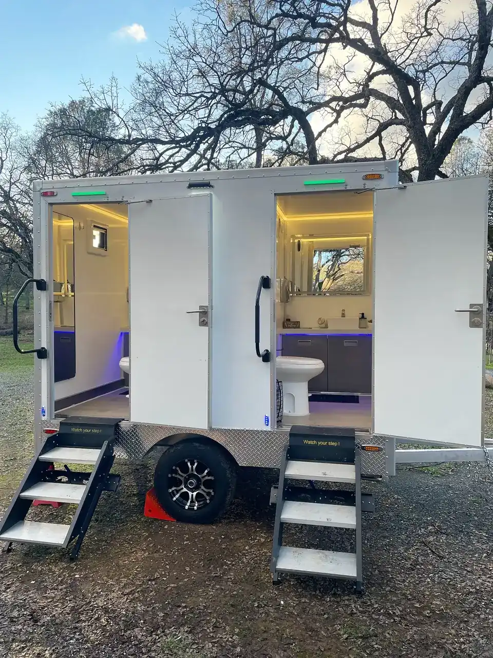 Restroom trailer set up for an event with both doors open and steps down