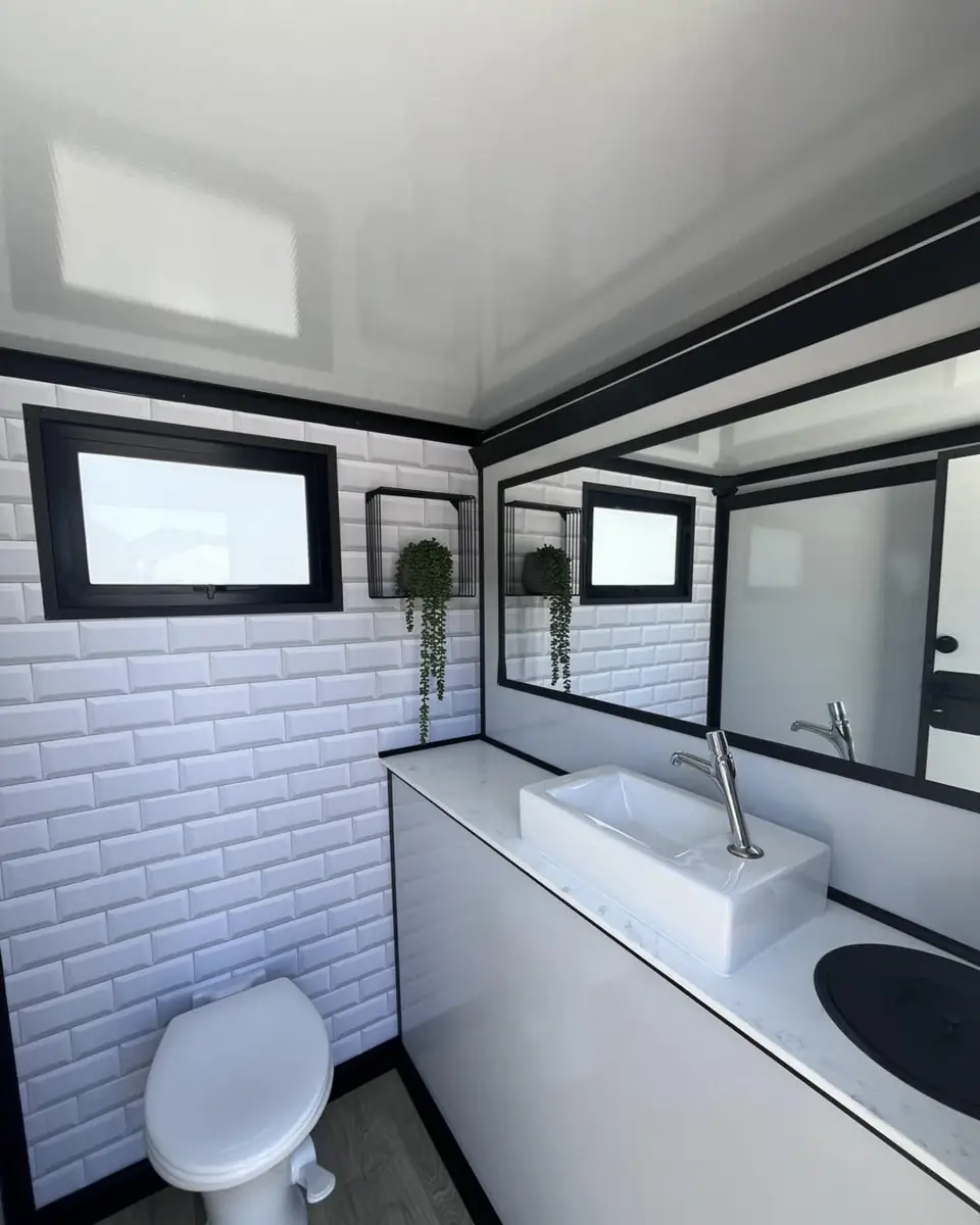 Restroom trailer interior with sink, mirror and window